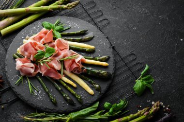 Haşlanmış kuşkonmaz ve siyah taş tabakta baharatlı jambon. Üst Manzara. Metnin için boş yer.