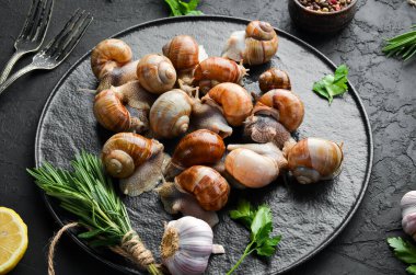 Siyah taş tabakta maydanozlu Taze Üzüm Salyangozu. Üst görünüm.