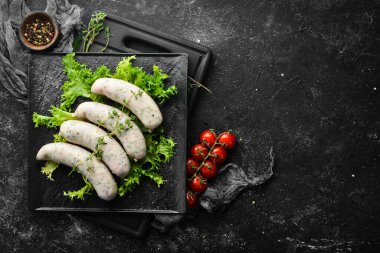 Siyah bir tabakta kekik ve baharatla çiğ sosis. Üst Manzara. Siyah bir arkaplanda.