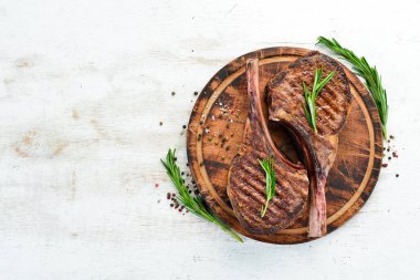 Kemiğe baharat ve otlarla Tamahavk bifteği. Beyaz ahşap bir arka planda. Üst Manzara. Boş kopyalama alanı.