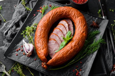 Taze biberiye ve baharatlı salam halkası. Siyah taştan bir arka planda. Üst Manzara. Metin için boş alan.