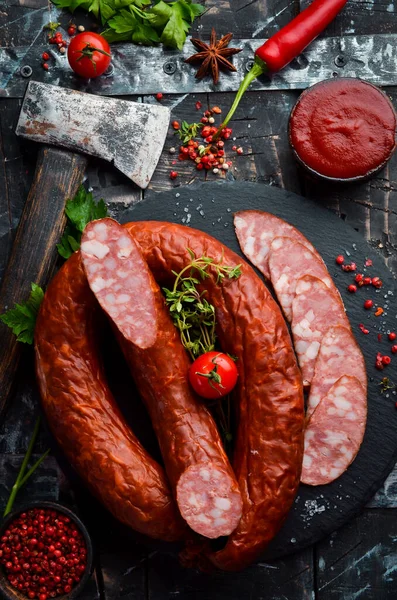 Rings of traditional smoked sausage in a country style composition. on a black stone background. Top view. Free space for text.