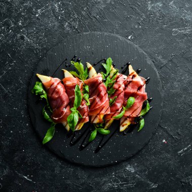 Siyah taş tabakta armut ve fesleğenli jambon. Jamon. İtalyan Antipasto. Üst görünüm.