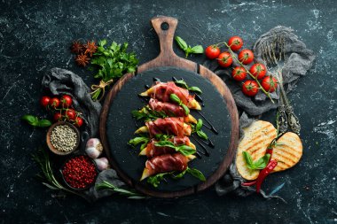 Siyah taş tabakta armut ve fesleğenli jambon. Jamon. İtalyan Antipasto. Üst görünüm.