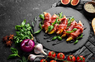 Siyah taş tabakta armut ve fesleğenli jambon. Jamon. İtalyan Antipasto. Üst görünüm.