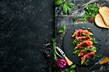 Siyah taş tabakta armut ve fesleğenli jambon. Jamon. İtalyan Antipasto. Üst görünüm.