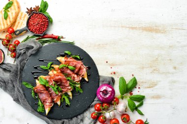 Siyah taş tabakta armut ve fesleğenli jambon. Jamon. İtalyan Antipasto. Üst görünüm.