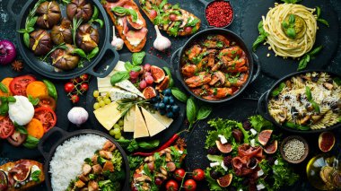 Yiyecek: peynir, incir, mantar, et ve sebze. Avrupa ve Asya mutfağı. Siyah taşlı arka planda sağlıklı yiyecekler. Üst görünüm.