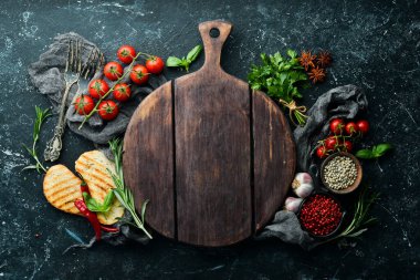 Siyah taş pişirme arka planı. Baharat ve sebze. Üst Manzara. Metnin için boş yer.