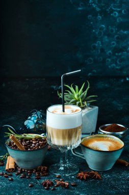 Kahve seti: kahve çekirdekleri, kahve ve kapuçino. Siyah bir arka planda. Üst görünüm.