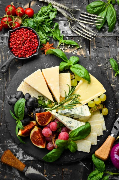 Assorted cheeses on a plate. Parmesan cheese, blue cheese and brie on a plate with grapes and figs. Antipasto. Top view.