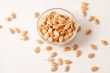 Kavrulmuş tedavi edilmezse kabak çekirdeği bir kase bir taş dokulu arka plan beyaz. Alan metni kopyalayın.