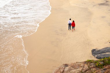 Tropikal yeşilliklerle çevrili ıssız sahilde aşık yürüme çift
