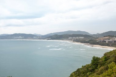 Tropikal ağaçlar ve bitki örtüsü deniz manzarası ile turistik kentin kıyısında büyük kayalar üzerinde