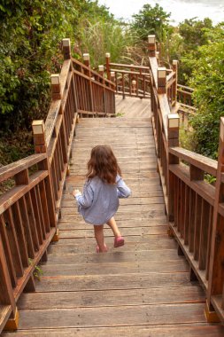 Tropikal bir ülkede bir çocukla seyahat. Dağlarda bir ahşap merdiven üzerinde zam. Arka plan resmi.