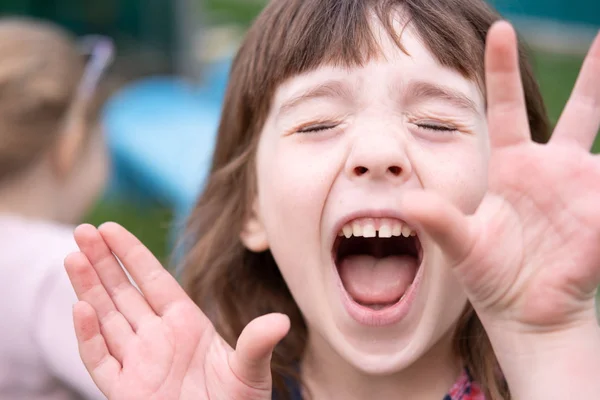 Een meisje van vijf jaar schreeuwd met vreugde het sluiten van zijn handen. Close-up gezicht. — Stockfoto