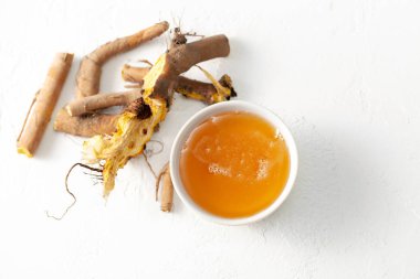 Ham kök bitki Rumex crispus (sarı rıhtım) ve beyaz beton arka plan üzerinde bal