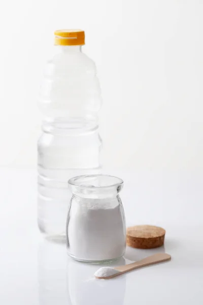 Un frasco de bicarbonato de sodio y una botella de vinagre en una mesa blanca — Foto de Stock