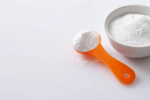 Cuchara medidora con edulcorante artificial aspartamo E951 y un bol de imperfecciones sobre fondo blanco brillante —  Fotos de Stock