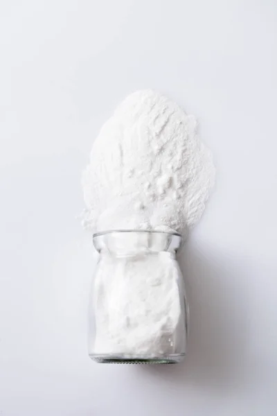 Scattered artificial sweetener aspartame E951 from a glass jar on white — Stock Photo, Image