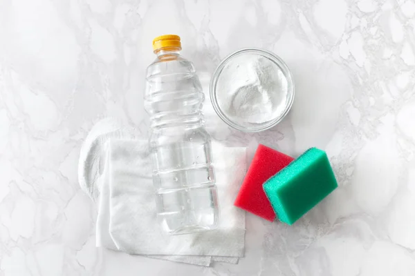 Vinegar in a bottle, baking soda and a cleaning cloth on a marble surface — Stock Photo, Image