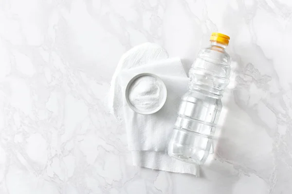 Vinegar in a bottle, baking soda and a cleaning cloth on a marble surface — Stock Photo, Image
