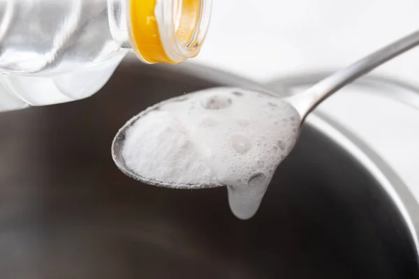 Mengocok baking soda dengan cuka dalam sendok di atas piring logam — Stok Foto