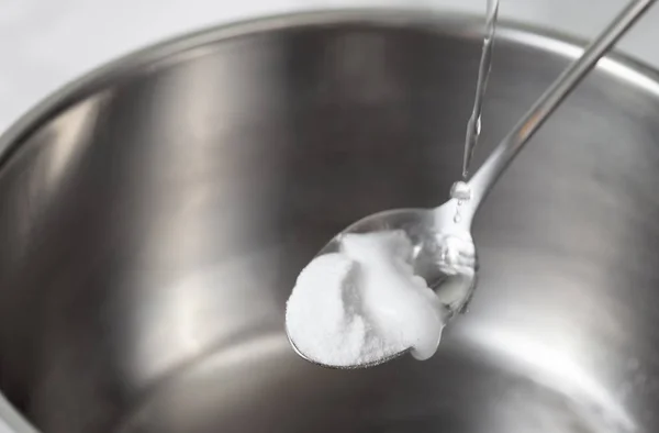 Espuma de bicarbonato de sodio saciado con vinagre en una cuchara sobre un plato de metal — Foto de Stock