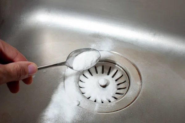 Выпечка соды в ложке над грязной раковиной посудомоечной машины — стоковое фото
