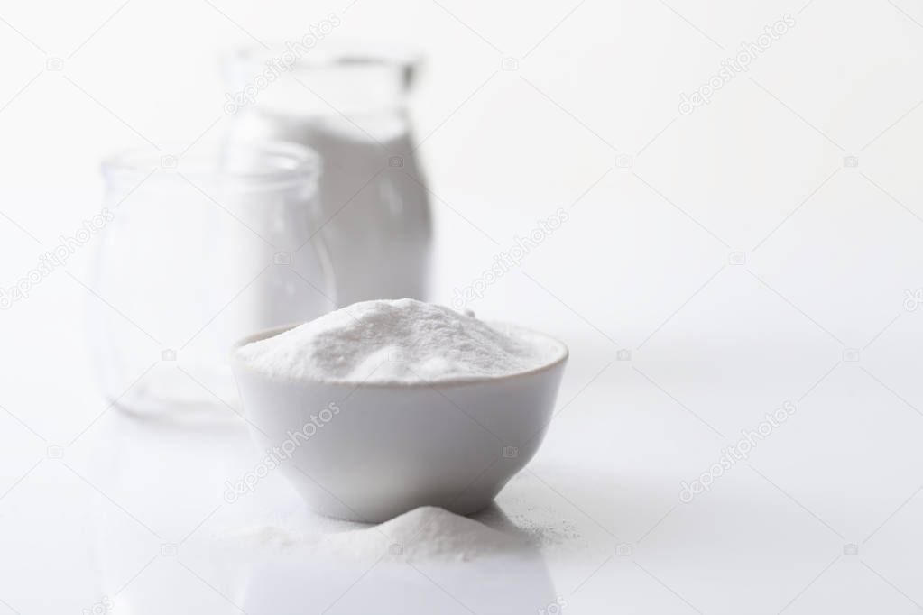 Jar with artificial sweetener aspartame E951 and a bowl on a white glossy background