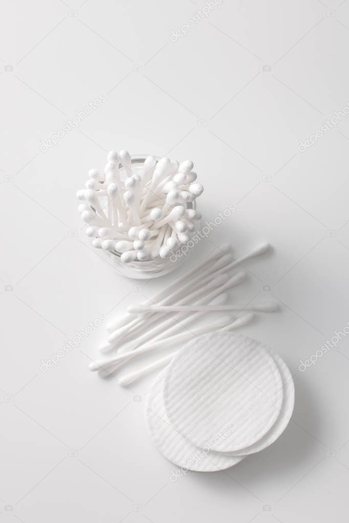 Cotton buds in a jar, cotton pads on a gray background.