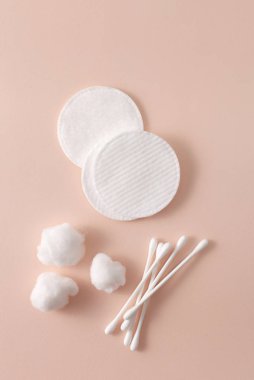 Pamuk pedler, pamuk çubuklar ve pembe bir arka planda pamuk parçaları.