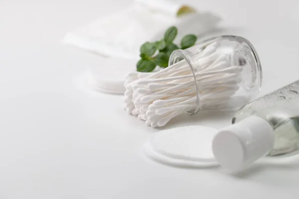 Cotton buds in a jar, cotton pads and a sprig of green — Stock Photo, Image