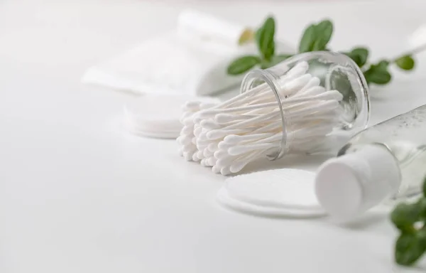 Cotton buds in a jar, cotton pads and a sprig of green — Stock Photo, Image