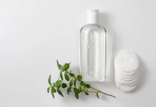 Micellar cleansing water in a bottle, cotton pads and a sprig of greenery — Stock Photo, Image