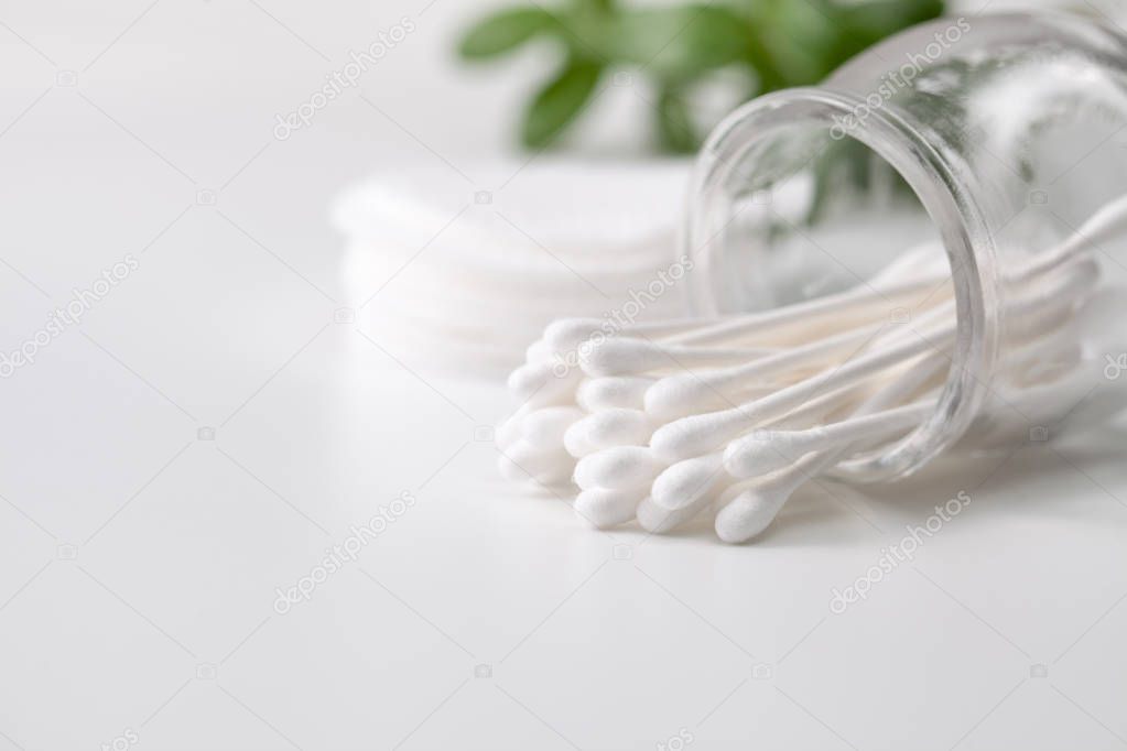 Cotton buds in a jar, cotton pads on a gray background.