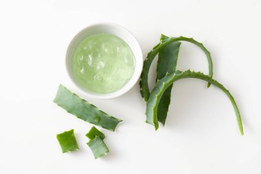 Aloe Vera yaprakları ve sıvı özünü kesiyor. Beyaz arka planda meyve suyu var.