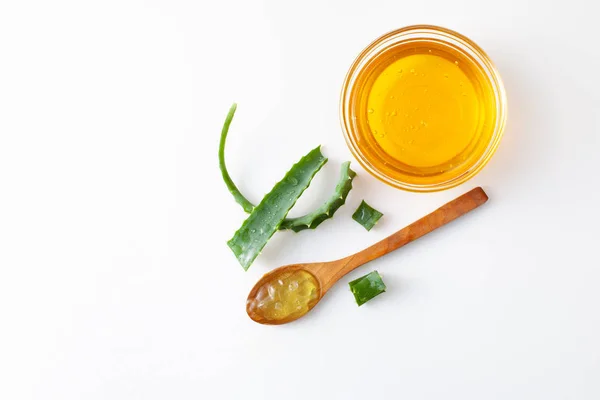 Aloe Vera cortó una hoja, el jugo de aloe en una cuchara y la miel sobre fondo blanco — Foto de Stock