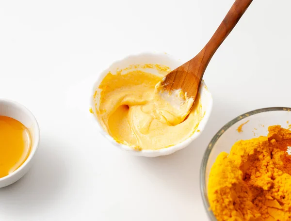 Rejuvenating homemade face mask made of honey and turmeric in a white bowl on the table. Copy space text.