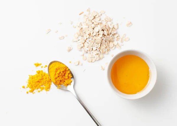 Recipe rejuvenating homemade face mask made of turmeric, honey and oatmeal on a white background. Copy space text.