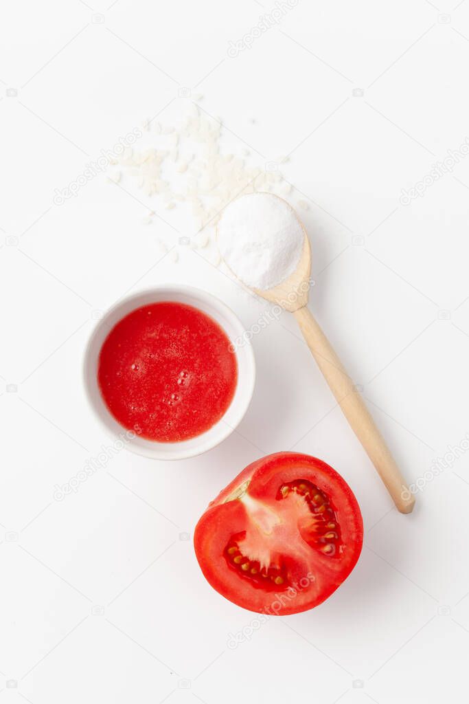 Top view of organic natural tomato juice and rice flour with a sliced tomato on a white background. Copy space text.