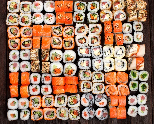 En mängd Sushi rullar på ett träbord — Stockfoto