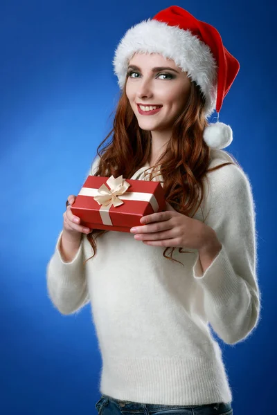 Happy woman wearing Santa hat holding gift box. Close up portrait with shoulders. — Stock Photo, Image