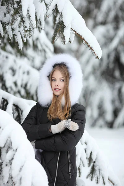 Retrato de mulher sorridente em roupas de inverno olhando para a câmera no parque nevado — Fotografia de Stock