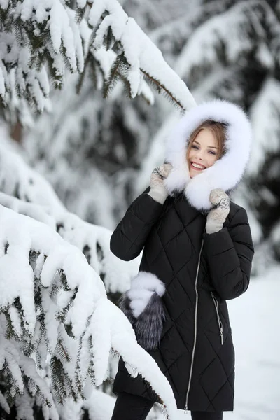 Retrato de mulher sorridente em roupas de inverno olhando para a câmera no parque nevado — Fotografia de Stock