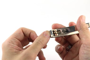 Tırnak makası sol elin tırnaklarını kesmek için kullanılıyor, tırnak sağlığını ve kişisel hijyeni temsil ediyor, tırnakları kesmek için temel araç, temizlik, hijyen ve ellerin kirliliğini korumak için