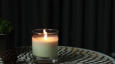 nice burning luxury aromatic scented candle glass is on marble table with a pine cone and background of grey stone curtain in bed room to create relax and romantic moment for lovers on Valentine day
