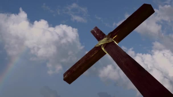 La Promesse Croix Atteindre les Cieux 4K dispose d'un gros plan croix inclinée vers le haut à partir du coin inférieur de l'écran avec des nuages mobiles et un soupçon d'un arc-en-ciel en arrière-plan 