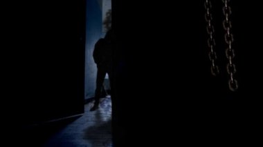 Hooded Man Behind Opening Door 4k Loop asılı zincirleri sallanan ve siyah kapüşonlu bir adam ortaya çıkarmak için açılan bir kapı ile karanlık bir oda özellikleri ve daha sonra bir döngü içinde tekrar kapanış