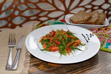 Vejetaryen salata sebze, roka ve Filiz quinoa ve ahşap masa Ajur ahşap arka plan üzerinde beyaz tabaklar Mayasız Ekmek. Çatal ve bıçak tabak yakınındaki.